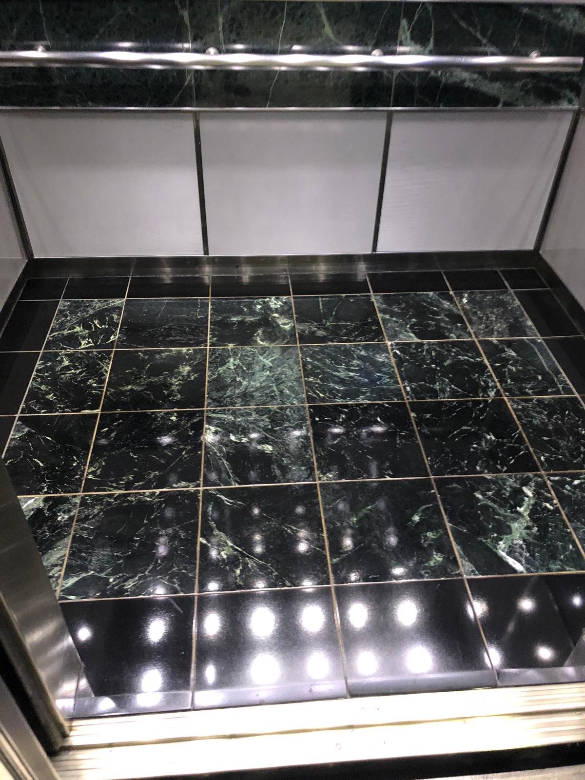 Elevator interior with polished dark tile flooring